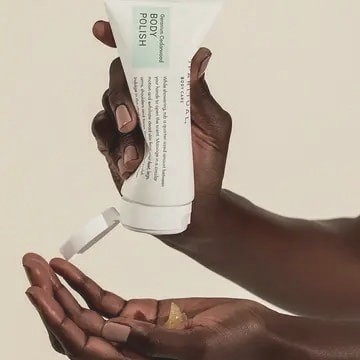 SpaRitual body polish poured between two hands on a warm backdrop
